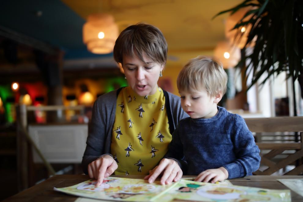 A lady with a kid browsing together printing materials