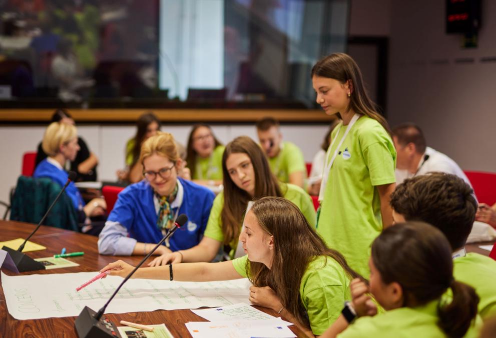 Young people working in groups and speaking into a microphone